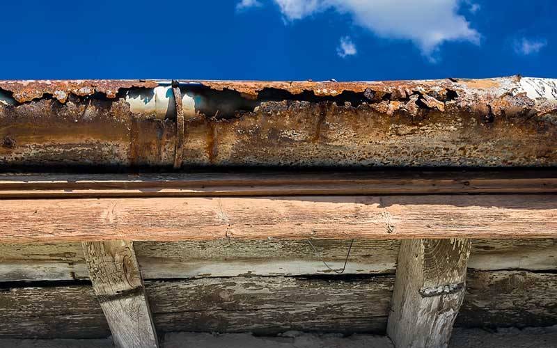 a rusty damaged gutter against the blue sky that needs replaced