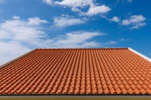 Red tiles panels roof under blue sky.