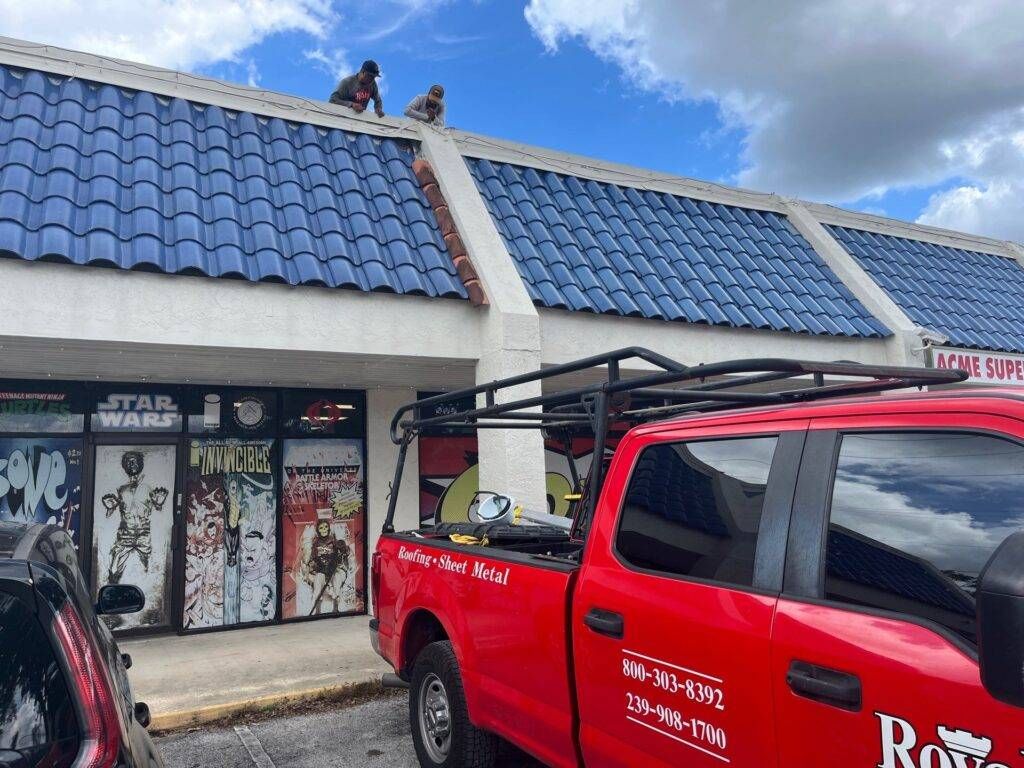 royalty roofers replacing tile metal roof on shopping center, workers leaning over awning with royalty truck parked in front