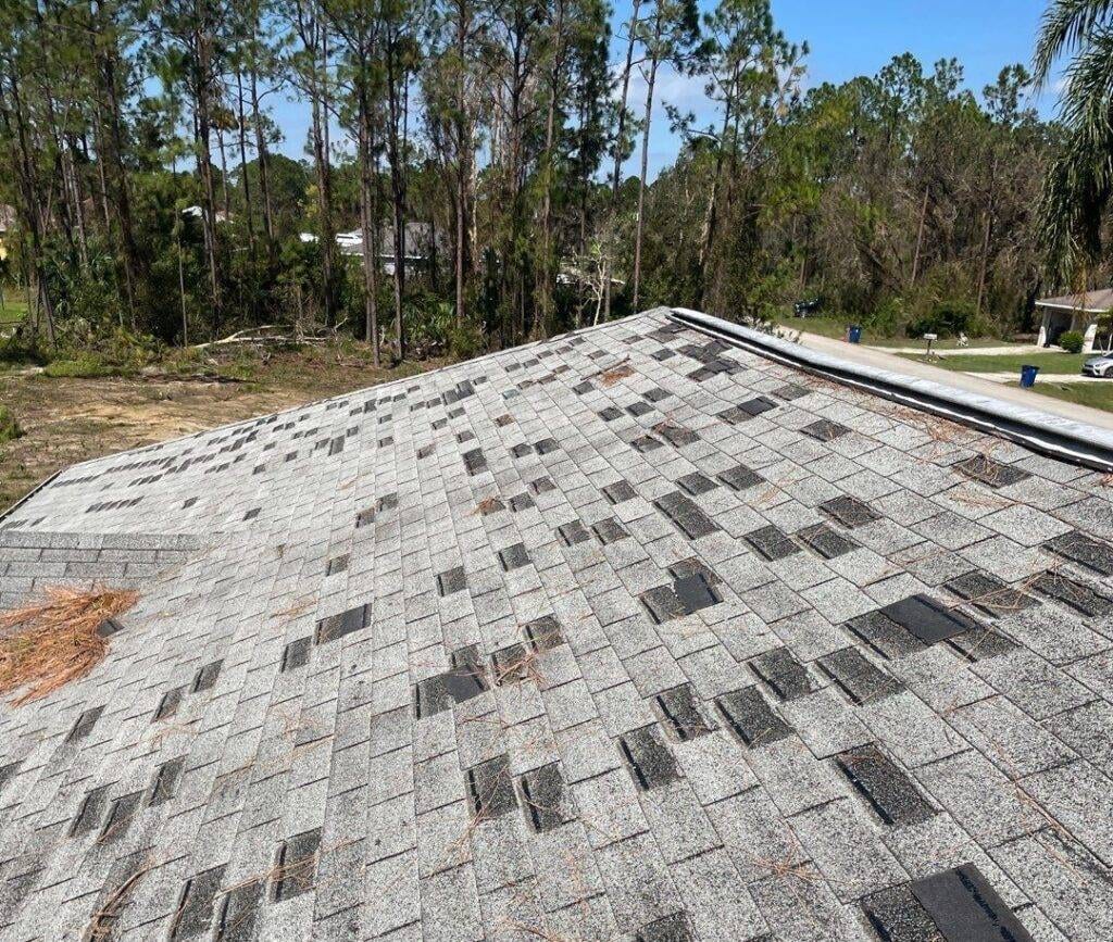 shingle roof damaged by storm with missing asphalt shingles