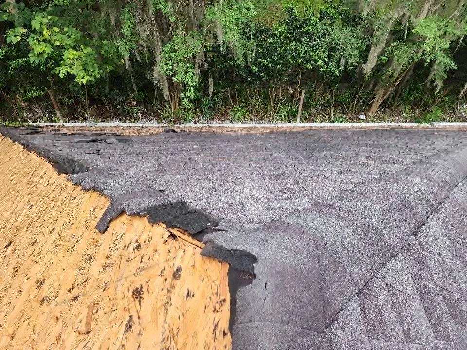 up close of shingle roof with shingles missing from half of roof from storm