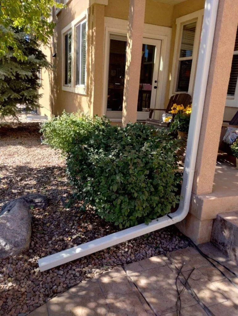 residential gutter downspouts on side of house flowing down into river rocks