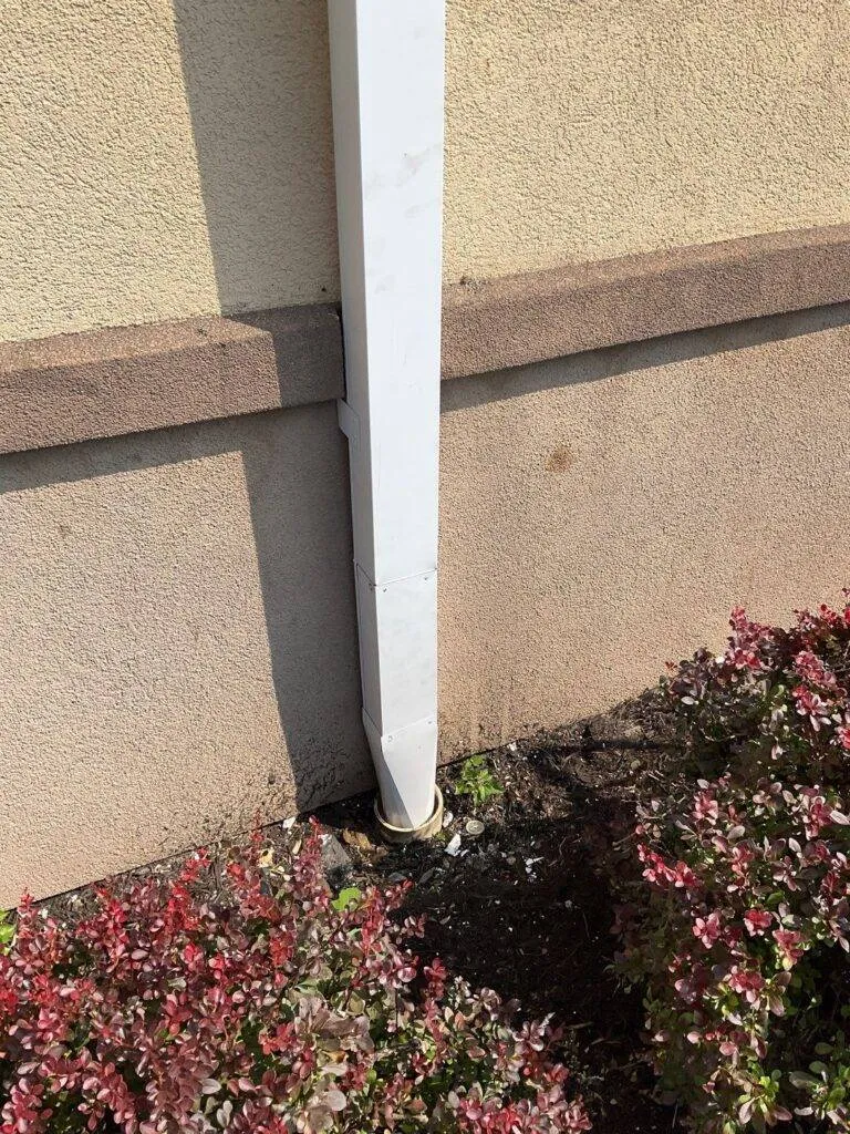 commercial gutter downspout running down side of building into landscaping
