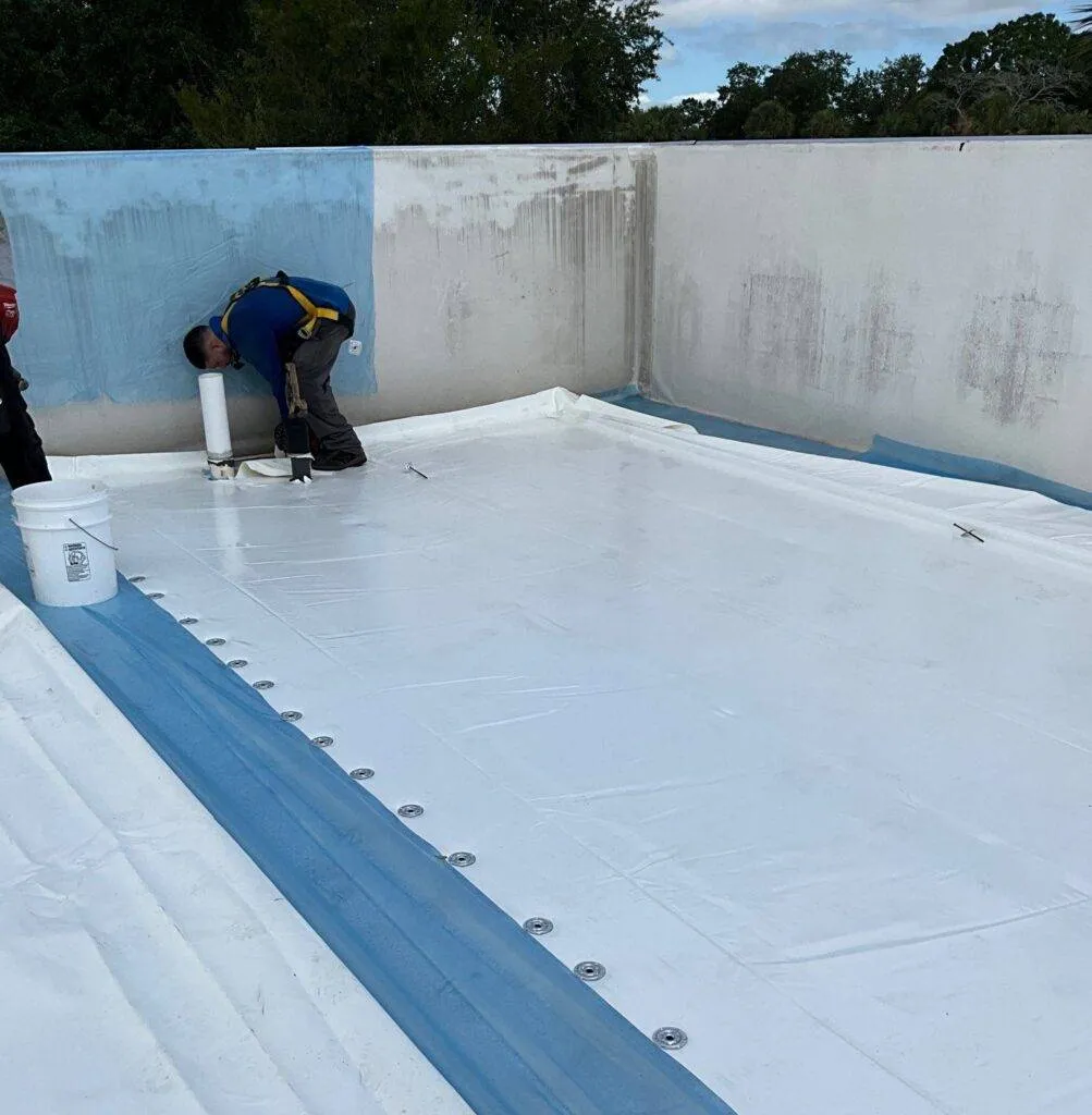 flat roof replacement in florida with roofer installing sheeting