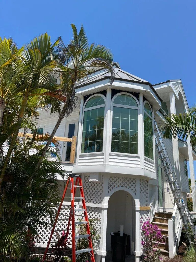 ladders against side of office building that looks like a home for gutter install