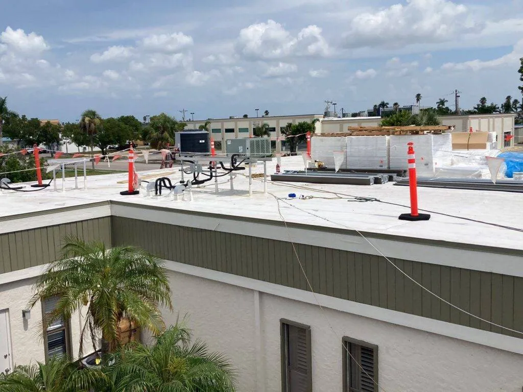 flat roof with caution cones and materials laid out during roof replacement