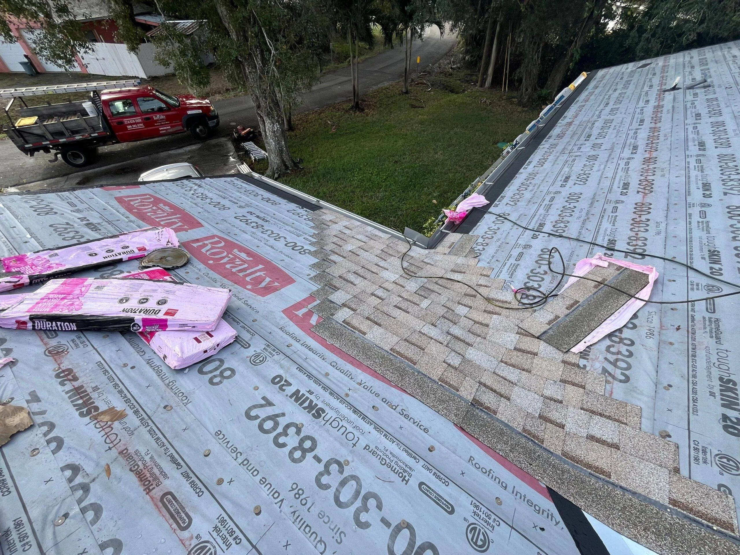 tan shingle tiles in the process of being laid with royalty roofing truck parked in the driveway