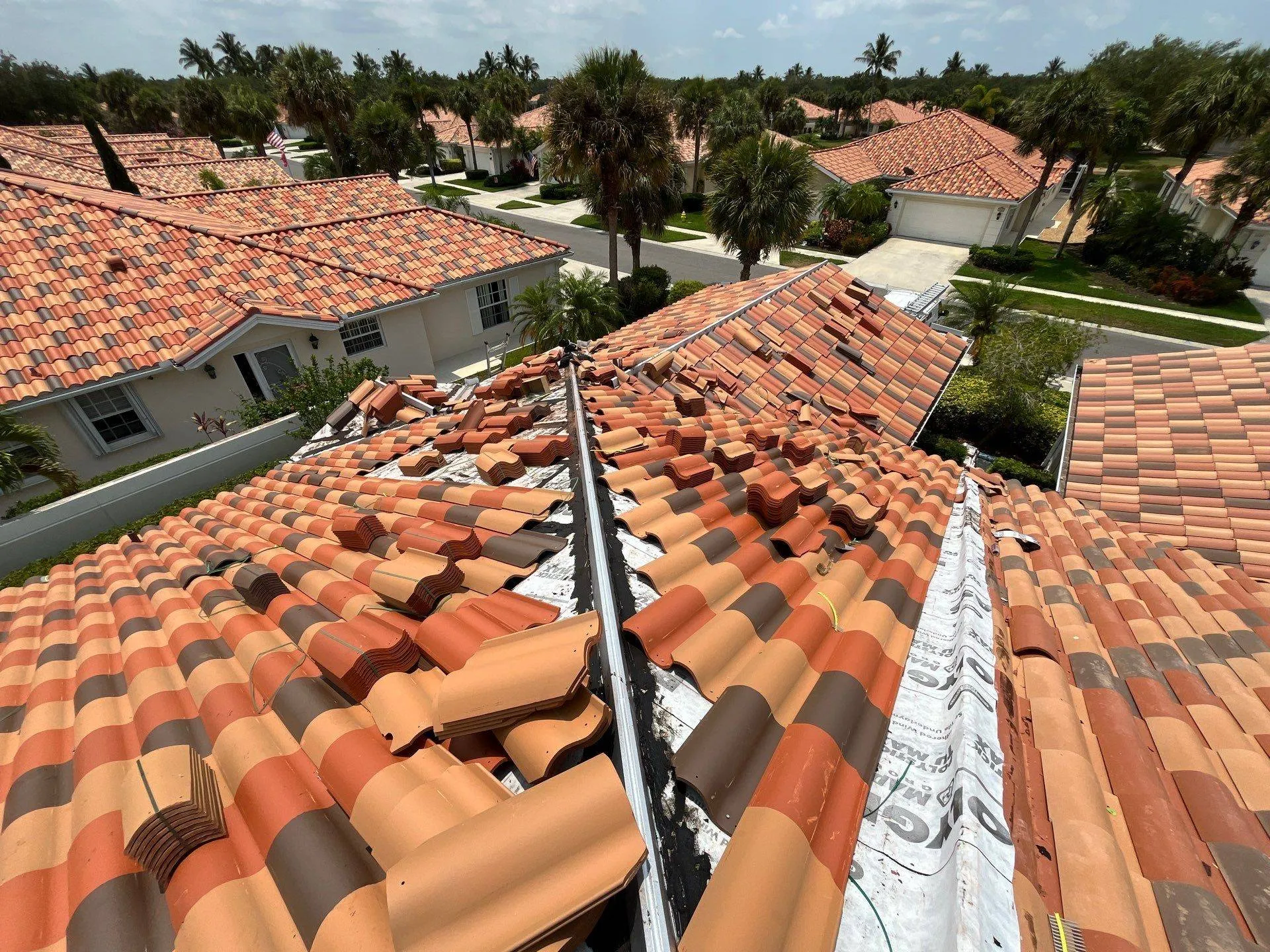 barrel tile roof in process of replacement in suburb in naples florida surrounded by homes with the same brown to red colored tiles