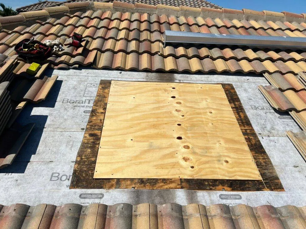 tile roof with tiles removed showing new board placed to repair water damage on roof